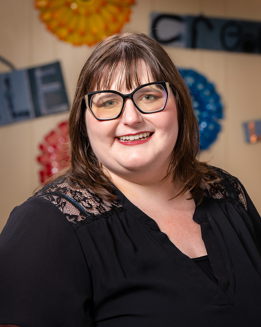 A woman with brown hair and glasses smiling at the camera.